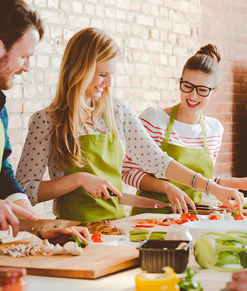 Adultes portant des tabliers verts en train de cuisiner dans un atelier culinaire